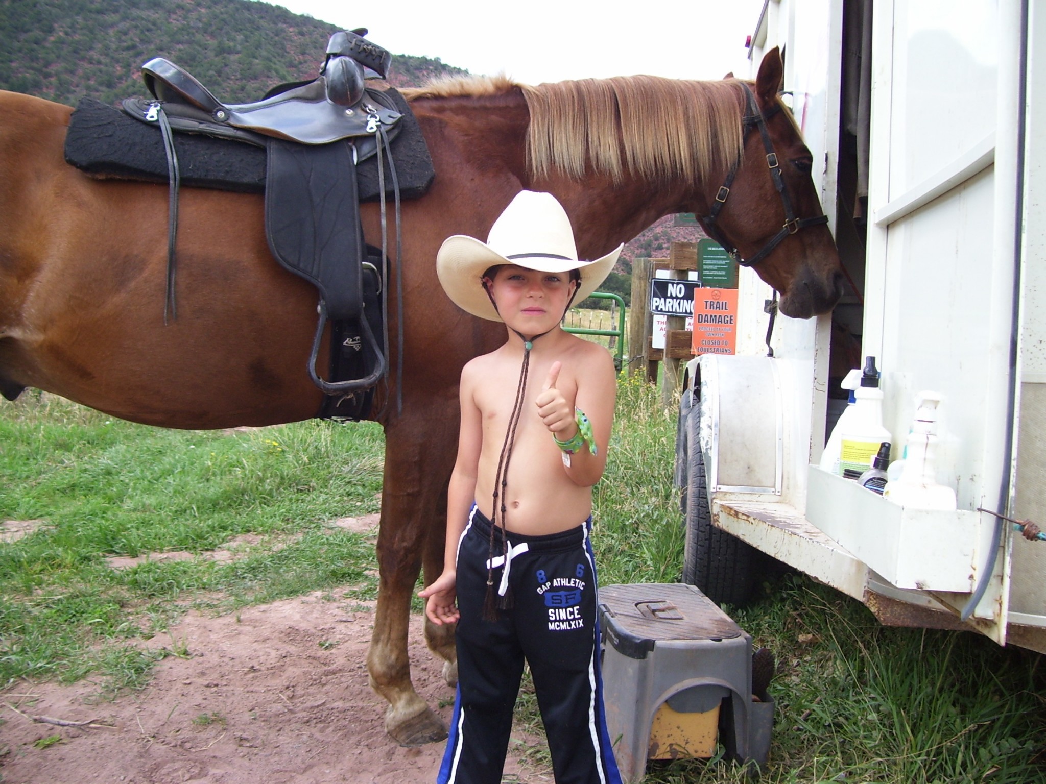 A childhood photo of Samo in a cowboy hat standing beside a horse.